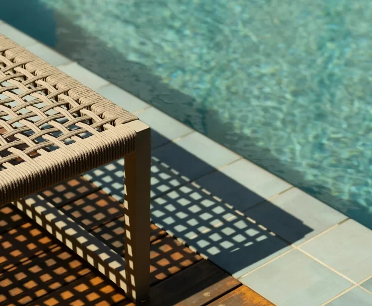 Woven lounge chair beside a backyard pool