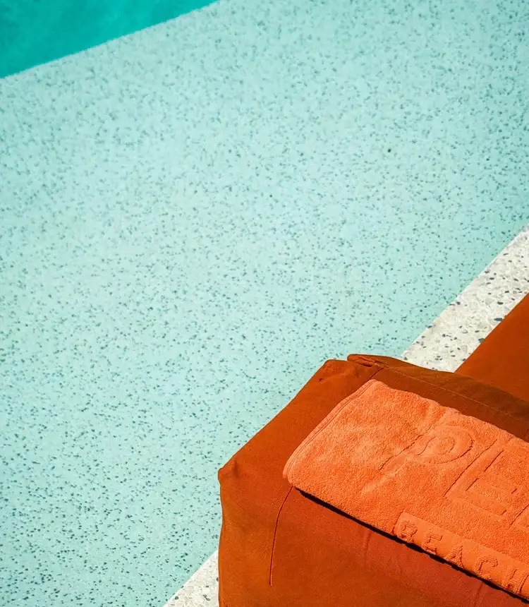 Light-blue pool finish beside an orange lounge cushion in San Luis Obispo