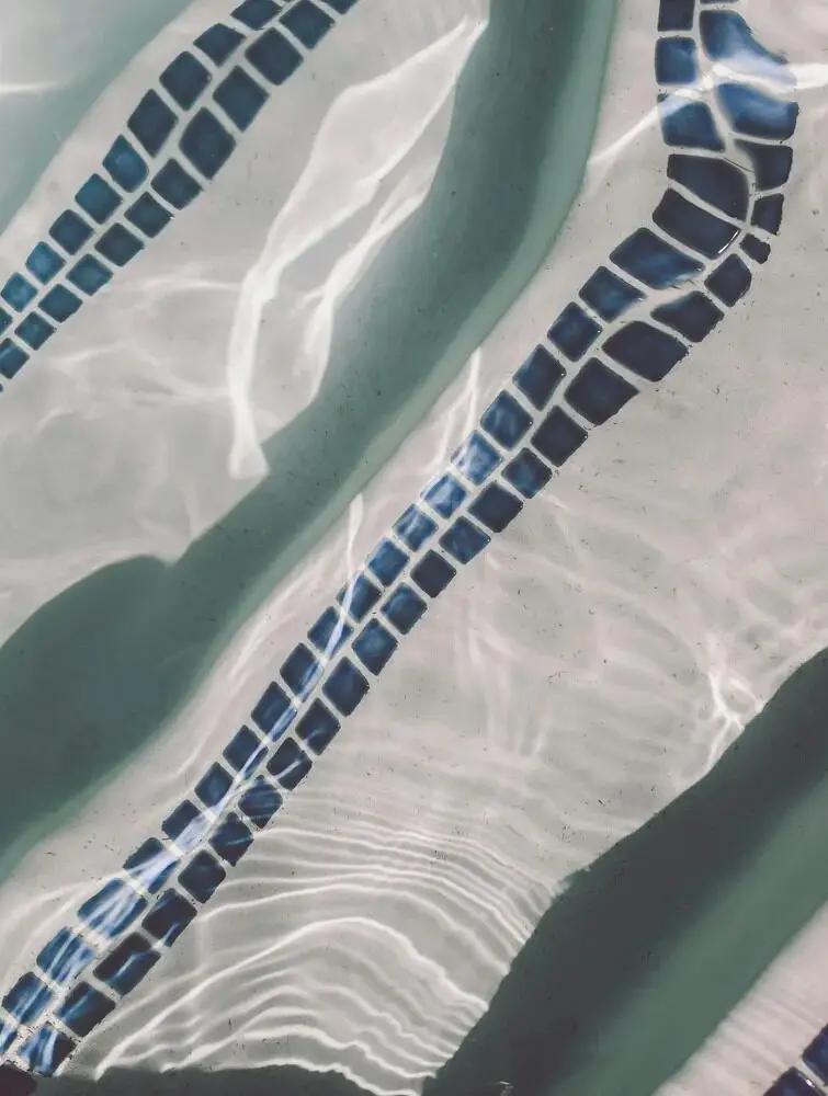 Mosaic tile line on the pool floor under rippling water