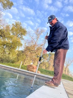 Pool Keepers technician cleaning a pool with a telescoping pole