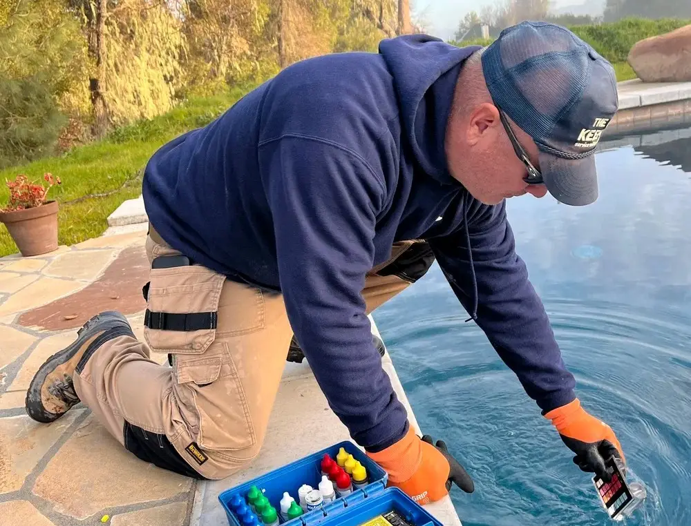 Technician testing pool water chemistry at the pool edge