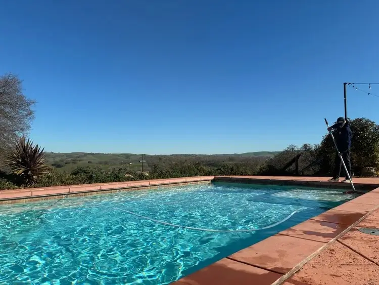 Clean pool with terracotta deck and hillside views