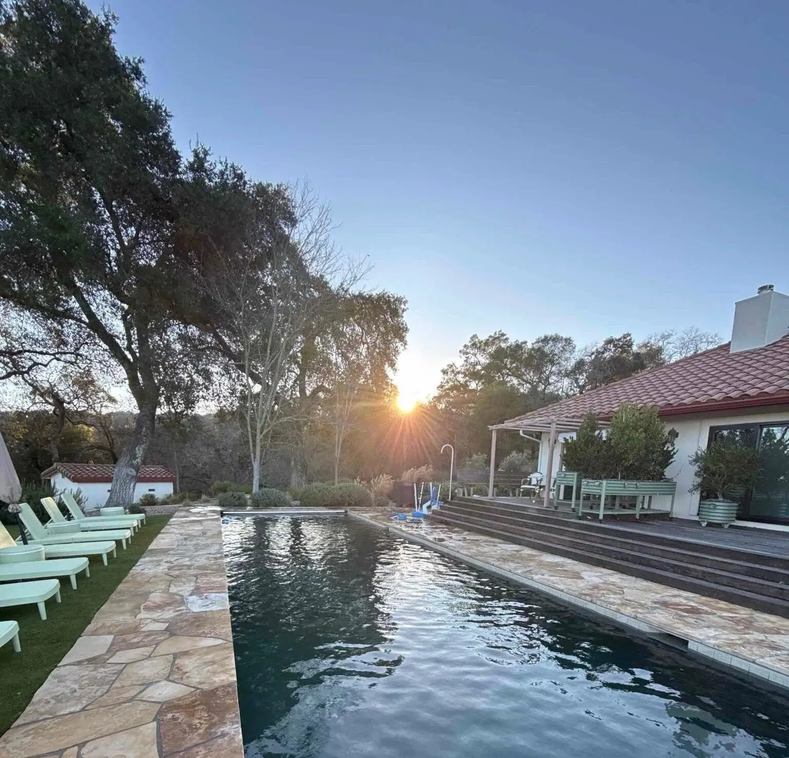 Rectangular pool at sunset with lounge chairs