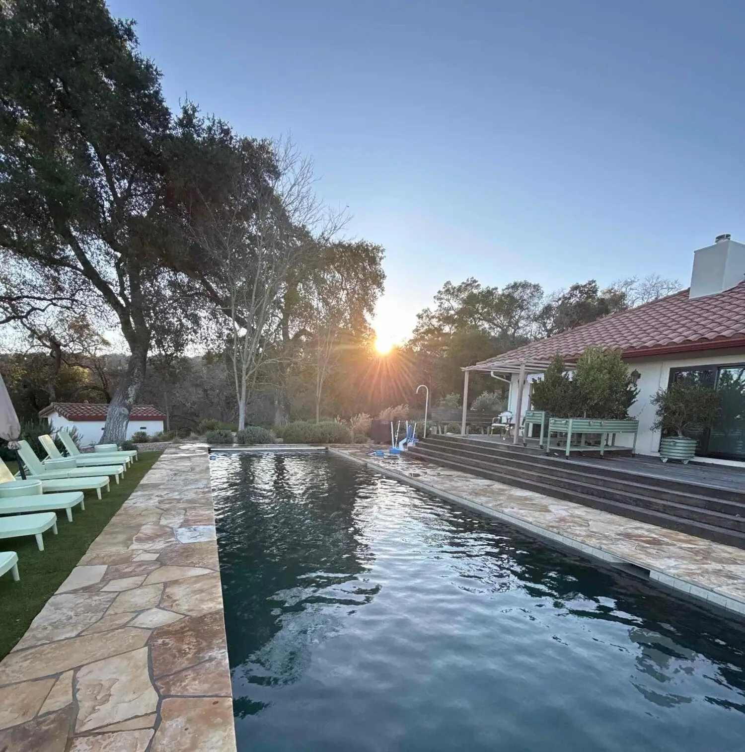 Long pool with stone deck and lounge chairs at sunset