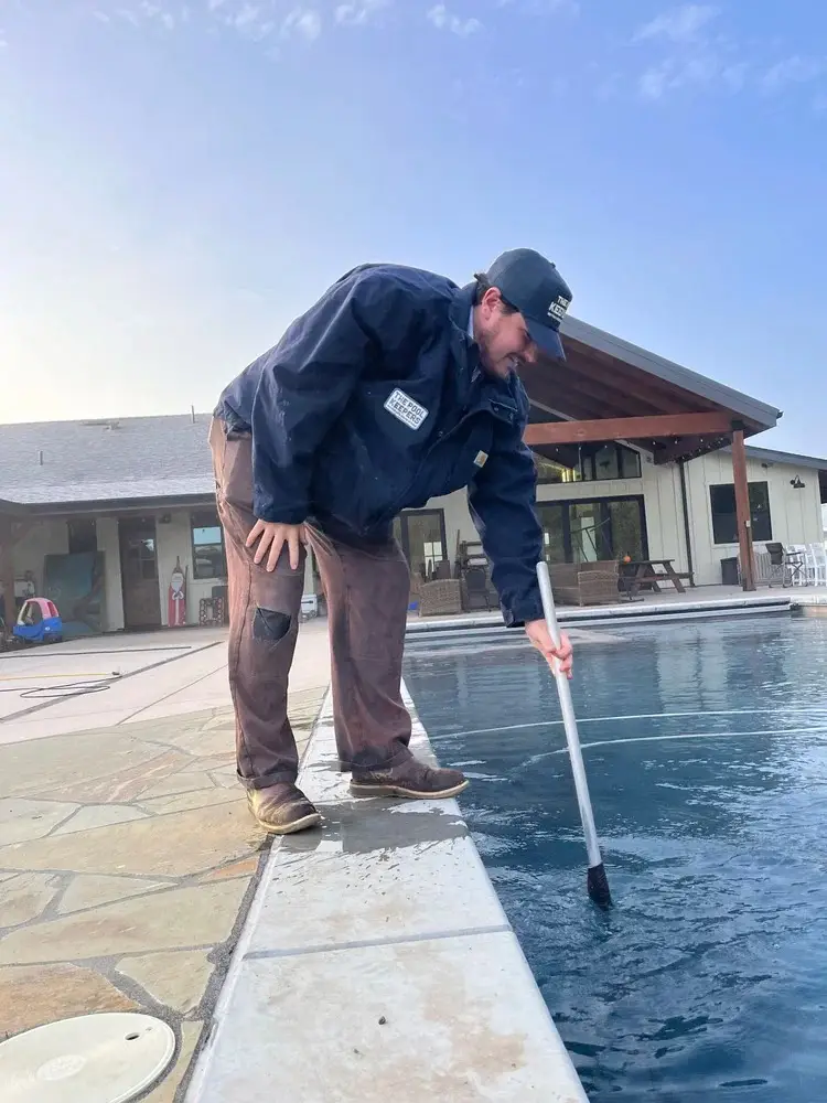 Pool Keepers technician cleaning a residential pool with a telescoping pole