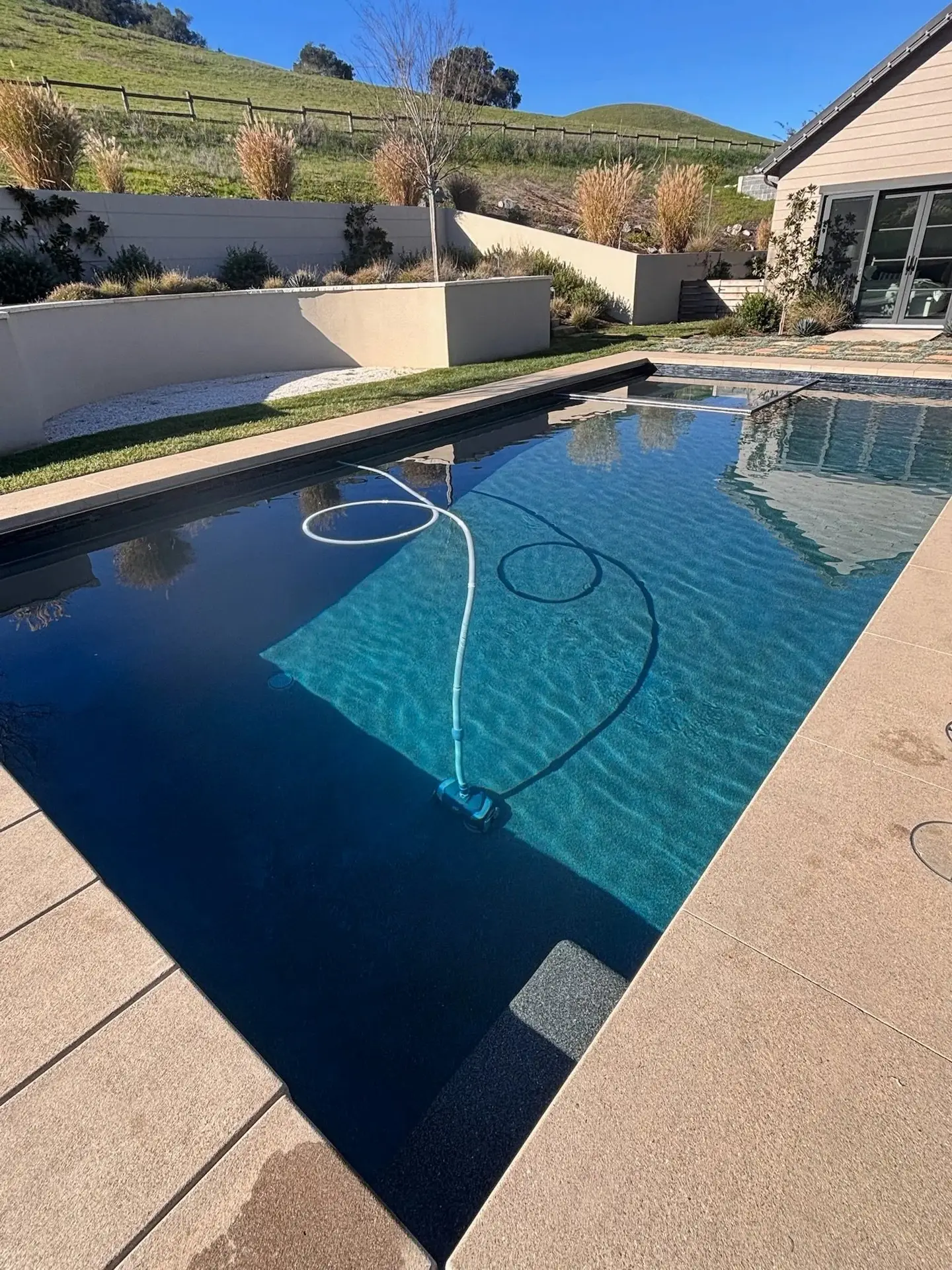 Dark-finish pool with automatic pool cleaner at a hillside home
