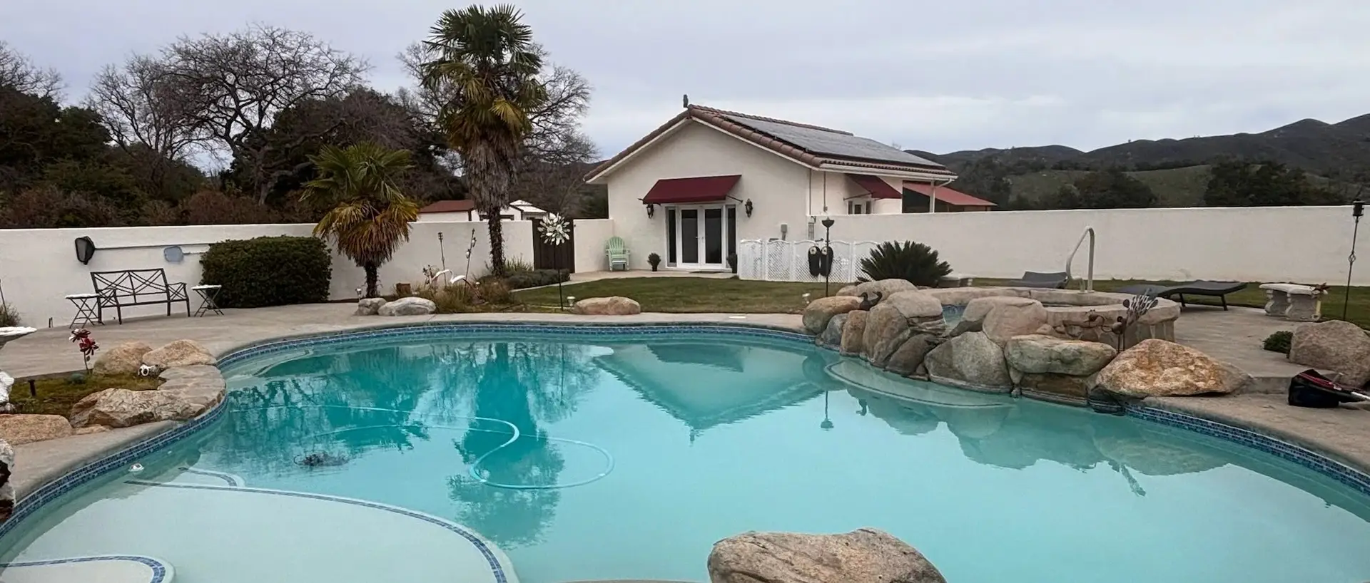 Freeform pool with rock accents in front of a home