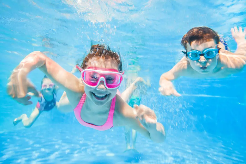 Kids swimming underwater with goggles in a clear pool