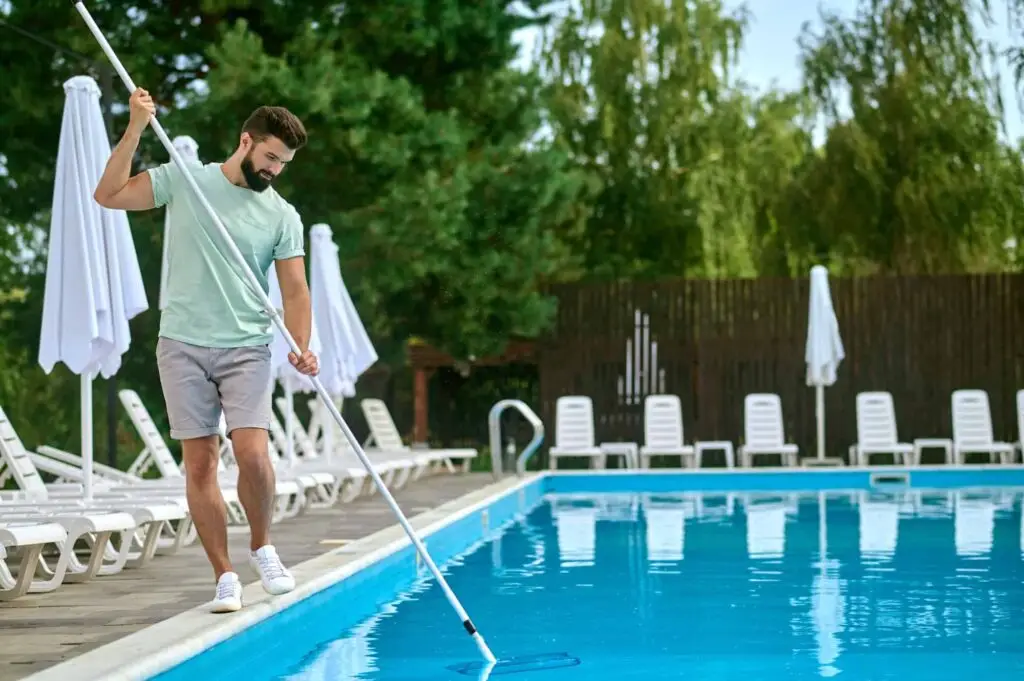 Pool Keepers technician vacuuming a pool lined with lounge chairs